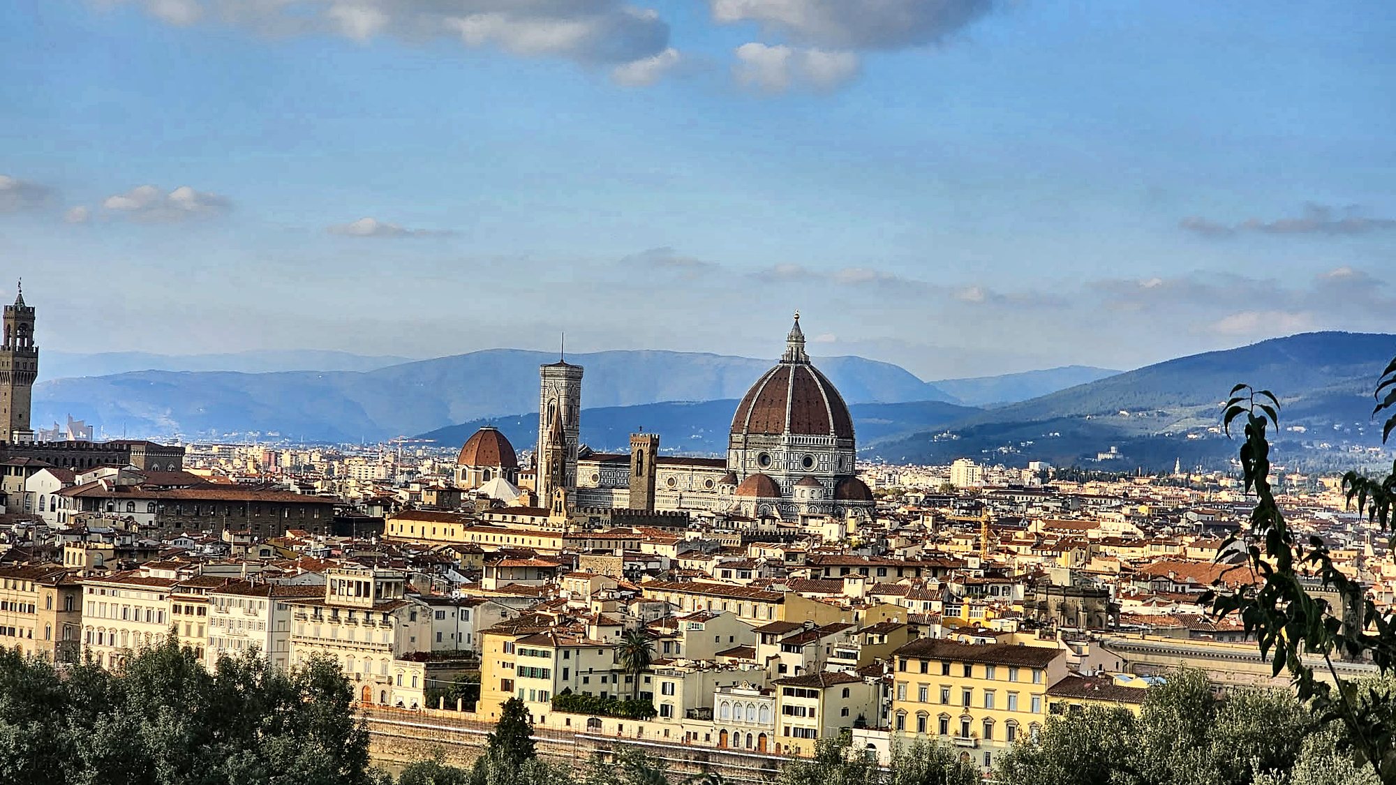 Florence seen from Piazzale Michelangelo: Brunelleschi's dome, Giotto's bell tower and Palazzo Vecchio above the terracotta rooftops, with the Apennine hills behind