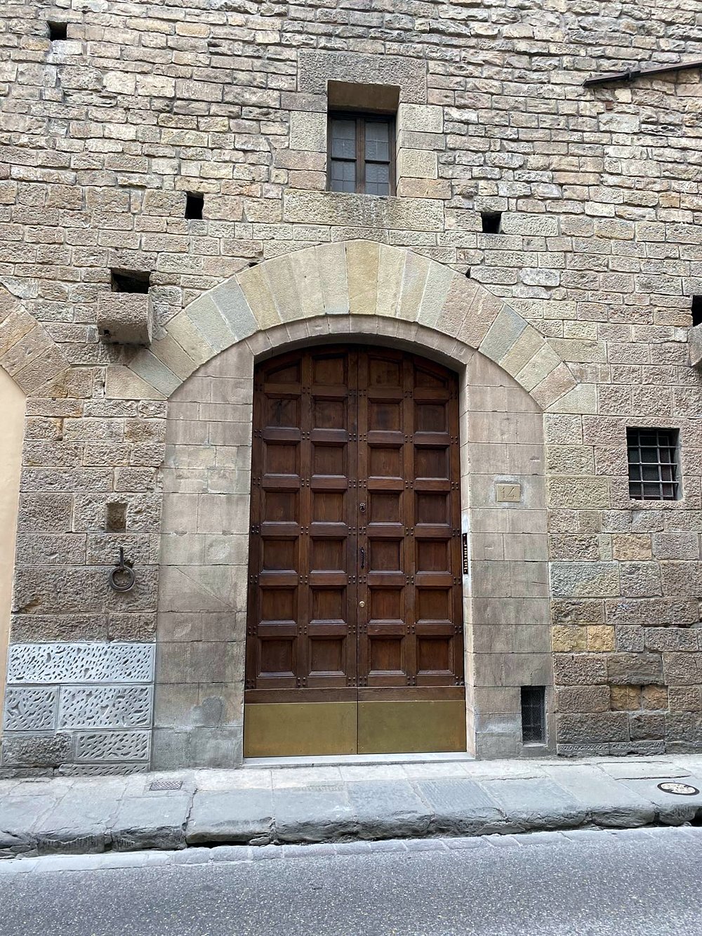 The arched wooden front door of Palazzo Pasqui at Via Bufalini 14
